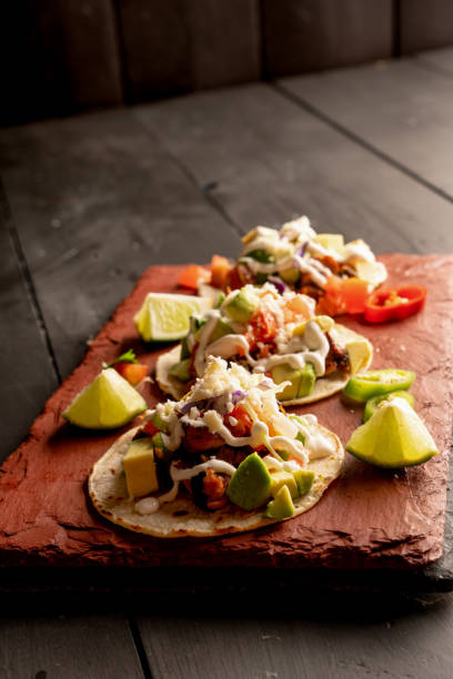 istock Pork Carnitas Tacos on a Rustic Slate Ready to be Served with Peppers, Lime, Salsa and Cotija Cheese 1200136825
