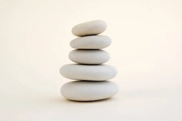 Photo of Harmony and balance, cairns, simple poise stones on white background, rock zen sculpture, white pebbles, single tower, simplicit