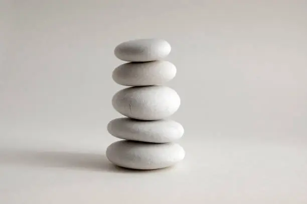 Photo of Harmony and balance, cairns, simple poise stones on white background, rock zen sculpture, white pebbles, single tower, simplicit