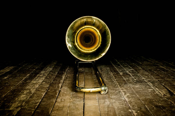 yellow brass instrument trombone lies on the wooden floor of the stage. front view on the bell - wind instrument imagens e fotografias de stock