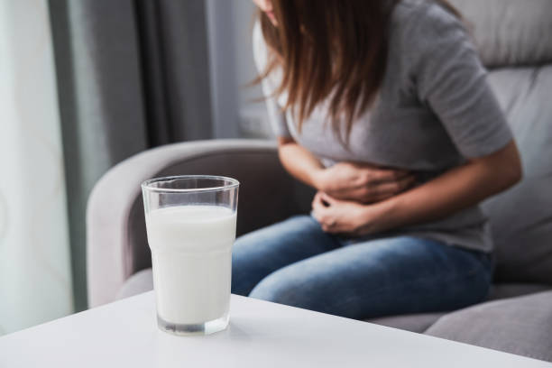 frau mit schlechten magenschmerzen mit einem glas milch, laktose-intoleranz, gesundheitskonzept - vorurteil stock-fotos und bilder