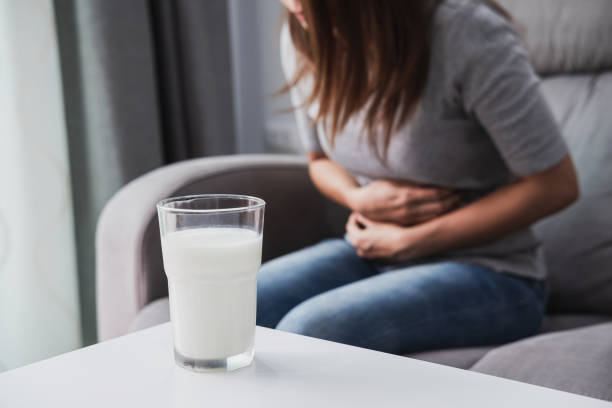 Woman having bad stomach ache with a glass of milk, Lactose intolerance, health care concept stock photo