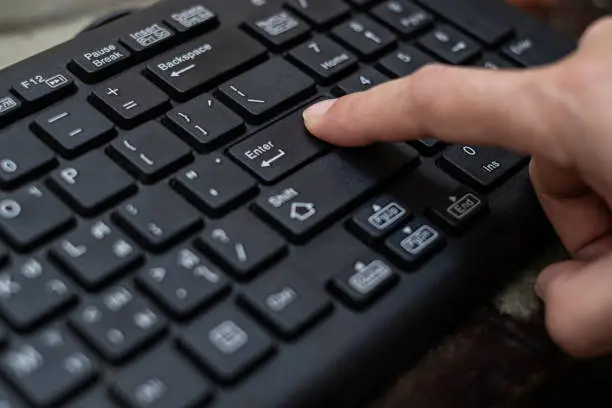 Photo of Close up Index finger push button Enter on the computer keyboard