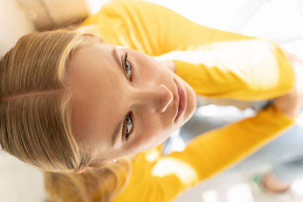 jeune dame concentrée dans le chandail jaune posant pour l'appareil-photo à la maison - women relaxation tranquil scene elegance photos et images de collection