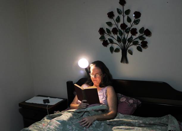istock middle-aged woman reading a book in her bed before bed 1200151758