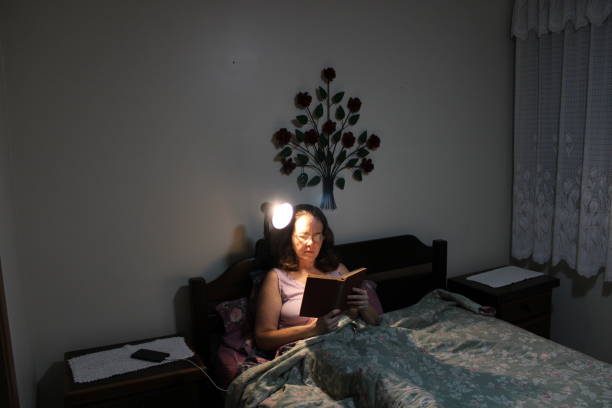 istock middle-aged woman reading a book in her bed before bed 1200151893