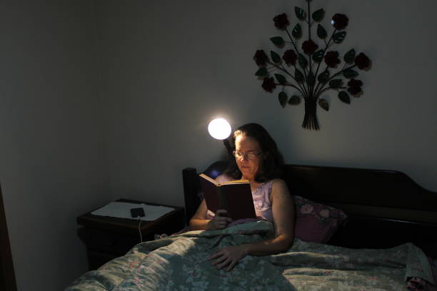 istock middle-aged woman reading a book in her bed before bed 1200151910
