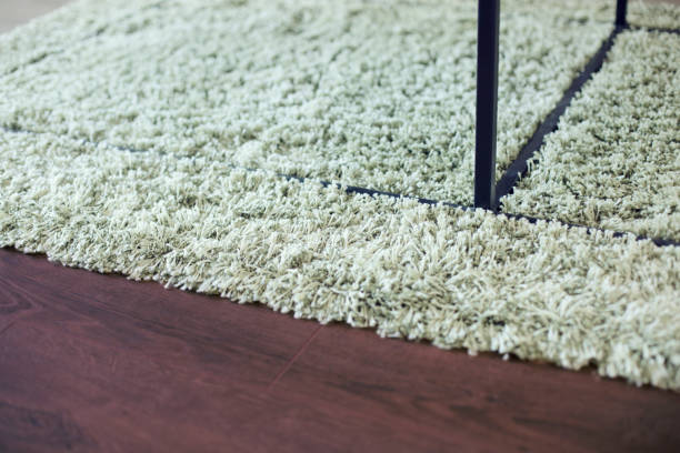 Carpet, laminate and metal table legs Close-up on beige shag rug, black metal table legs and brown laminate floor. shag rug stock pictures, royalty-free photos & images