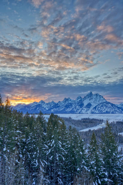 Vibrant Sunset in the Winter at Christmas in the Grand Tetons National Park and Yellowstone National Park USA Vibrant sunset in the winter at Christmas time in the Grand Tetons National Park and Yellowstone National Park area. As the snow forms a thick blanket across the Tetons Range, wildlife becomes more visible and the scenery more dramatic than then the busy summer season. snake river valley grand teton national park stock pictures, royalty-free photos & images