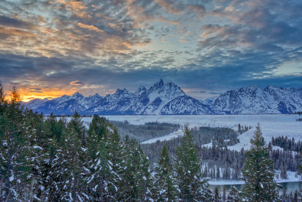 Vibrant Sunset in the Winter at Christmas in the Grand Tetons National Park and Yellowstone National Park USA Vibrant sunset in the winter at Christmas time in the Grand Tetons National Park and Yellowstone National Park area. As the snow forms a thick blanket across the Tetons Range, wildlife becomes more visible and the scenery more dramatic than then the busy summer season. snake river valley grand teton national park stock pictures, royalty-free photos & images