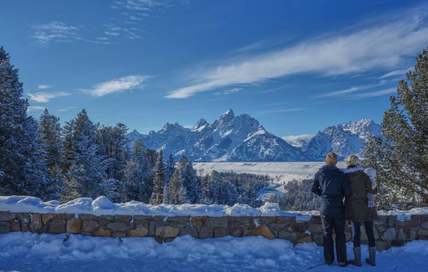 family taking in the view in the winter at christmas in the grand tetons national park and yellowstone national park usa - snake river teton range mountain range mountain imagens e fotografias de stock