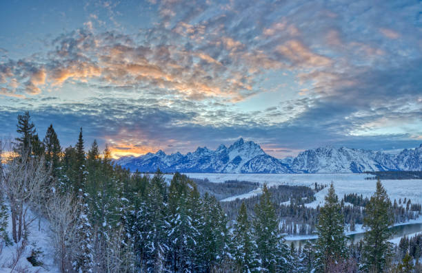 Vibrant Sunset in the Winter at Christmas in the Grand Tetons National Park and Yellowstone National Park USA Vibrant sunset in the winter at Christmas time in the Grand Tetons National Park and Yellowstone National Park area. As the snow forms a thick blanket across the Tetons Range, wildlife becomes more visible and the scenery more dramatic than then the busy summer season. snake river valley grand teton national park stock pictures, royalty-free photos & images