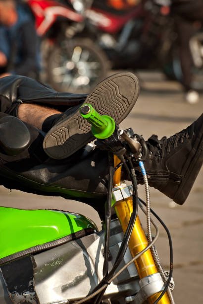 istock Motorcycle steering wheel closeup. Chrome steering wheel elements. The man threw his legs on the steering wheel. The guy is resting on a motorcycle. 1200157716