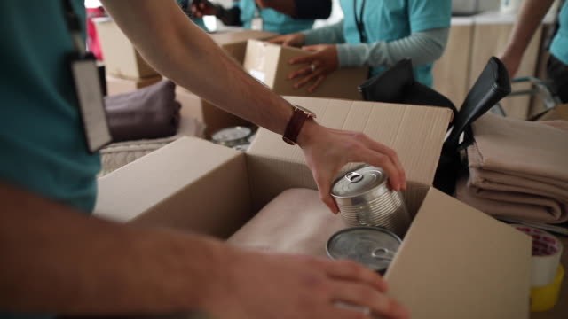 Young man working at charitable foundation, packing donation box