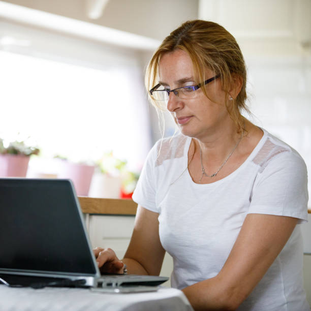 istock Middle-aged woman using laptop at home 1200166535