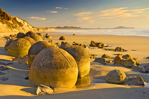 The Moeraki Boulders are unusually large and spherical boulders lying along a stretch of Koekohe Beach on the wave cut Otago coast of New Zealand between Moeraki and Hampden.