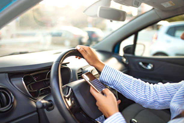istock Woman using phone while driving behind the wheel. 1200171350