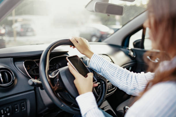 istock Side View Of Young Woman Using Mobile Phone While Driving Car 1200172097