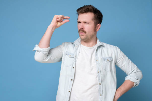 istock Young caucasian man gesturing with hand showing small size sign with fingers. 1200173675