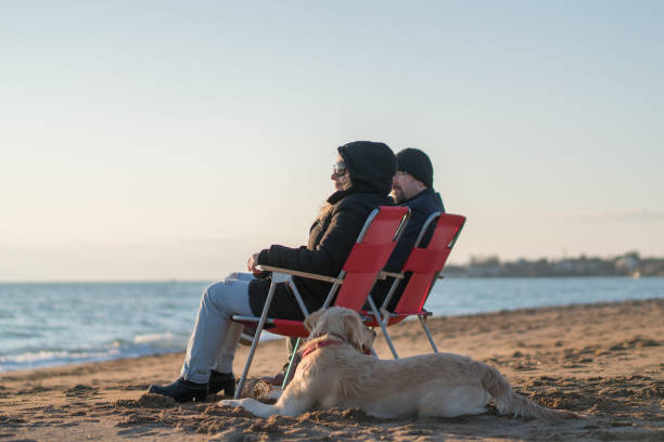 Couple relax on beach with dog  at winter