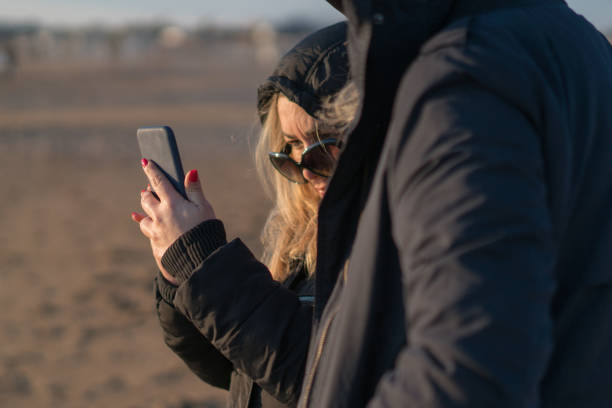 istock Young woman using phone on the beach 1200181646