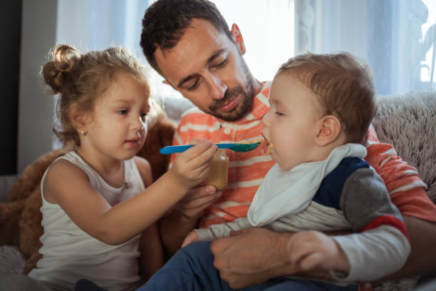 istock Sister feeding her brother with dad 1200184599