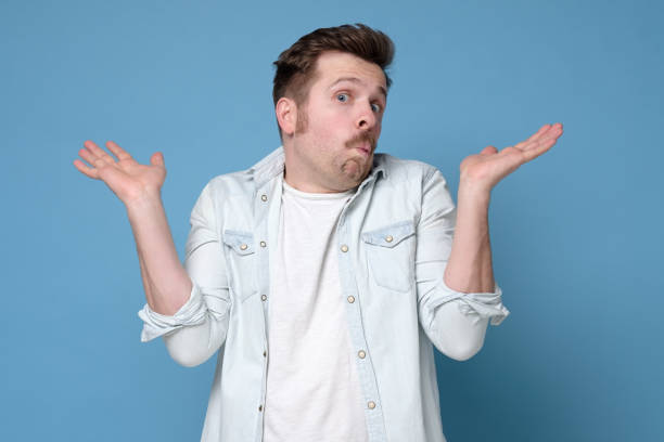 istock Confused caucasian man is unsure in studio shrugging shoulders up 1200185545