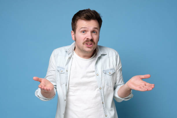 istock Handsome man with mustache looking questioned standing with spread hands over blue background. 1200185588