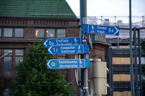 Many directional signs mounted on a pole in the crossing in Helsinki, showing cyclists and pedestrians the routes to famous places