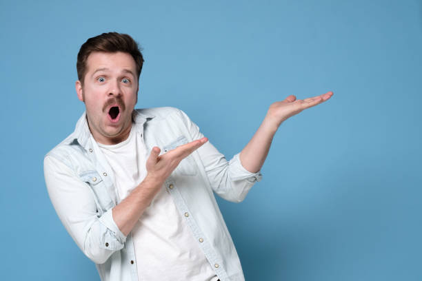 istock Man with mustache show empty copy space on open palm gesture for your ad, demonstrate advertise product saying wow 1200188375