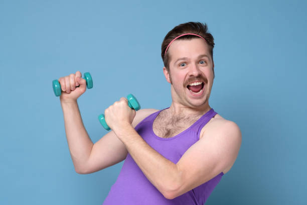 istock Humorous athletic man using small dumbbells for bodybuilding 1200188407