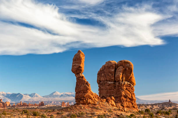 Wispy Clouds Above Balanced Rock WIspy bird-like clouds over iconic Balanced Rock against the La Sal Mountain in Arches National Park in Moab, Utah. la sal mountains stock pictures, royalty-free photos & images