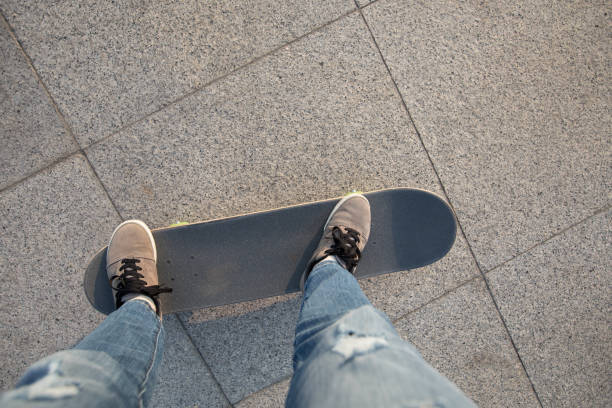 A young Caucasian girl plays outside, scooting around on skateboards and wearing helmets for safety and protection.  View from above looking down.