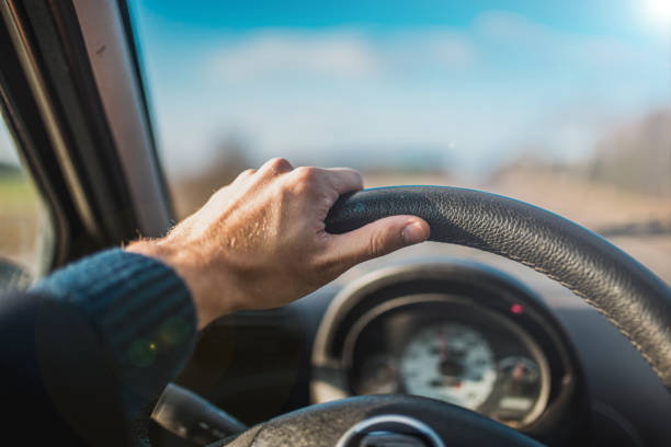 istock car driver on a summer sunny day holds the steering wheel with his hands. 1200193084