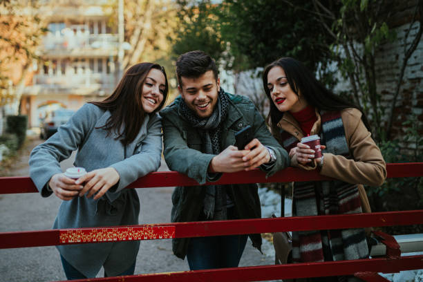 istock Two young women and one young man using smart phone 1200203544