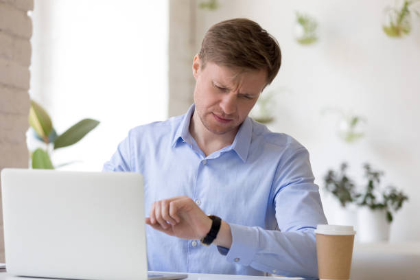 frowning mittleren alters unternehmer blick auf armbanduhr, warten auf partner. - human nervous system fotos stock-fotos und bilder