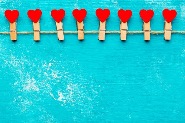 Valentine day background with red decorative hearts on rope and clothespins at rustic blue wooden table. Happy Valentine lovers day card mockup. Free space for your text.