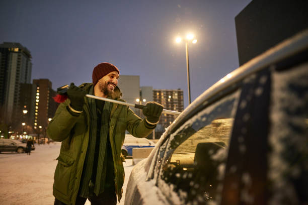 My duty after a blizzard Shot of a man removing snow from his car during cold winters evening scraper stock pictures, royalty-free photos & images
