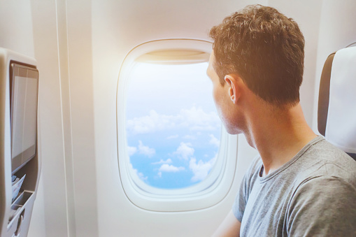 passenger of airplane looking at window, international travel, happy man tourist enjoy flight in comfortable air plane