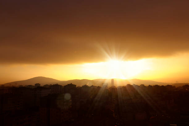 elevated view of smoky cityscape image over orange color sunset sky in Istanbul