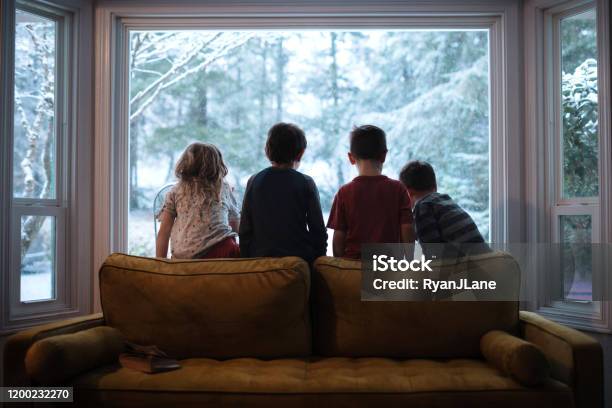 Children Looking Out The Window At Falling Snow Stock Photo - Download Image Now - Winter, Window, Family