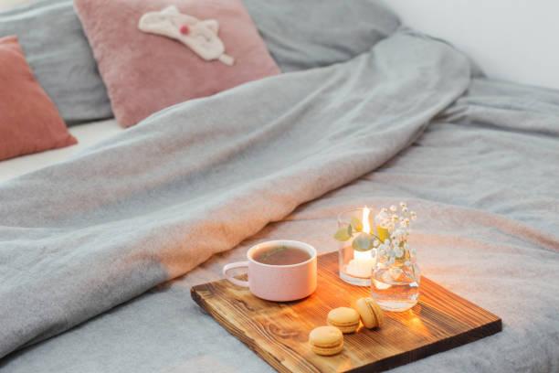 istock herbal tea with macaroons and candles on wooden tray on bed 1200241906