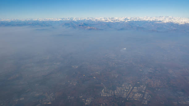 이탈리아의 포 밸리를 덮고있는 스모그와 안개의 공중 보기.  비행기 창에서 풍경입니다. 낮은 비와 바람으로 인한 오염. 배경에서 알프스 - padan plain 뉴스 사진 이미지