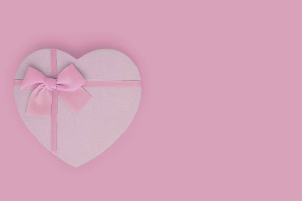 istock Light pink heart shaped gift box with ribbon bow on pink background 1200246142