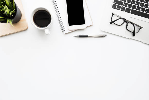 istock White office desk table with smartphone with blank mock up screen, laptop computer, cup of coffee and supplies. Top view with copy space, flat lay. 1200255955
