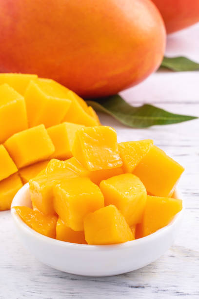 istock Fresh mango,beautiful chopped fruit with green leaves on bright wooden table background. Tropical fruit design concept, close up, copy space. 1200261194