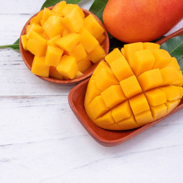 istock Fresh mango,beautiful chopped fruit with green leaves on bright wooden table background. Tropical fruit design concept, close up, copy space. 1200261206