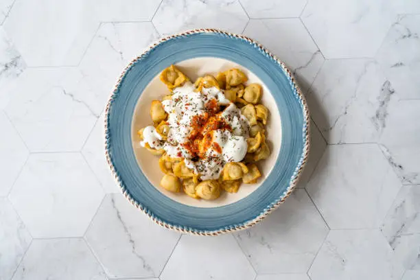 Photo of Homemade Russian Pelmeni Fried Dumplings with Meat, Yogurt, Tomato Sauce and Spices.