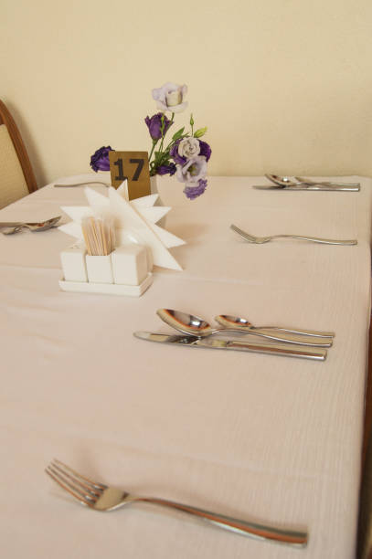 istock Close-up of elegant silver Cutlery on an empty, white set table, VERTICAL FRAME, serving waiting for guests 1200274900