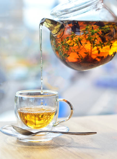 istock From a glass kettle pour tea into a glass cup on a light background 1200277010